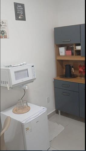 a kitchen with a microwave on top of a refrigerator at COLOFT - Studio Térreo com Acessibilidade in Anápolis