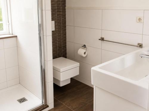 a white bathroom with a toilet and a sink at Pet-Friendly Coastal Getaway in Breskens