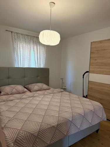 a bedroom with a large bed and a chandelier at Apartman Ilaria in Medulin