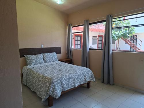 a bedroom with a bed and two windows at Hotel Casa del virrey Atlixco in Atlixco
