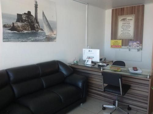 sala de estar con sofá de cuero y escritorio en Hotel Dal Gobo, en Ponta Grossa