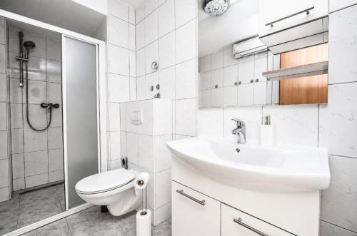 a white bathroom with a sink and a toilet at Mikuljan Apartments- Free Parking -5 Min by Walk to Beach in Stobreč