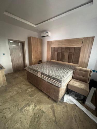 a bedroom with a large bed and a chair at sky 7 hotel & apartment in Akure