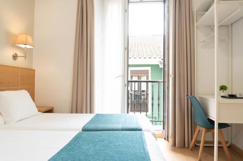 a hotel room with a bed and a desk and a window at Musika Plaza in Zarautz