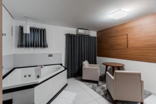 a bathroom with a tub and a table and chairs at Romas Hotel in Umuarama