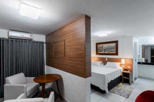a bedroom with a bed and a table and a chair at Romas Hotel in Umuarama