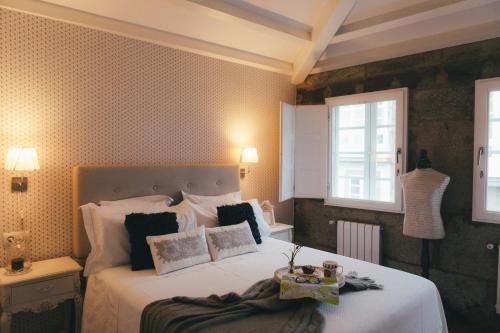 - une chambre avec un grand lit et des draps blancs dans l'établissement Apartamentos Aurelia Antica, à Saint-Jacques-de-Compostelle