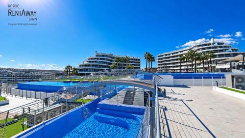 a bridge over a swimming pool with two buildings at Infinity View Apartments by NRAS in Arenales del Sol