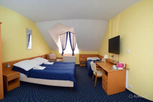 a hotel room with two beds and a desk at Aladin Praha in Prague