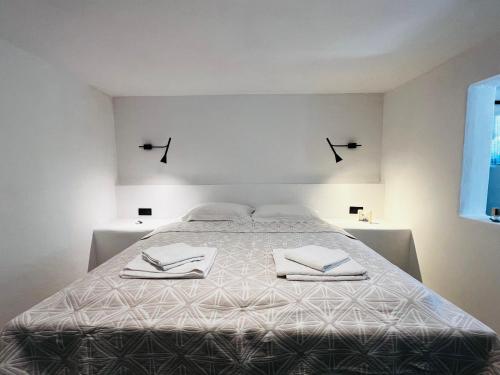 a white bedroom with a large bed with towels on it at Aloni Petit House in Nerotriviá