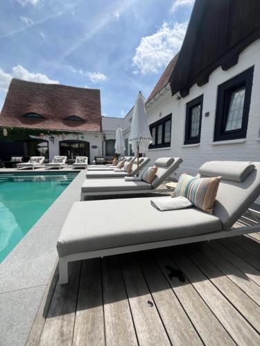 a row of lounge chairs next to a swimming pool at The Cotton Suites B&B in Deerlijk