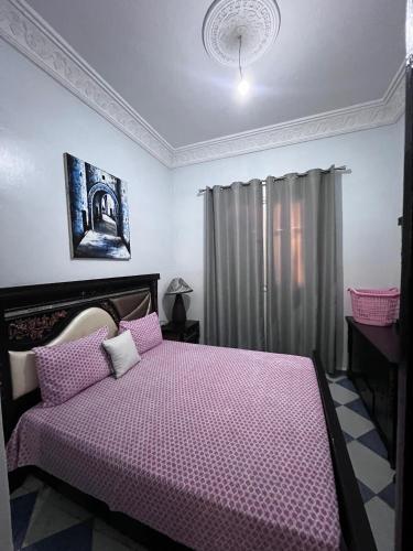 a bedroom with a bed with a pink comforter at Appartement Maroc Safi in Safi