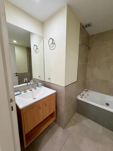 a bathroom with a sink and a tub and a mirror at Suite Pinamar 09 in Pinamar