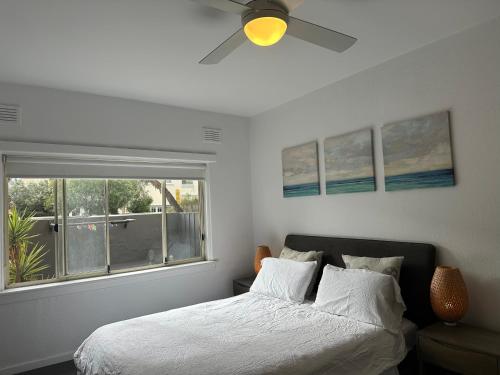 a bedroom with a bed with a ceiling fan and a window at Beachfront Apartment in Melbourne