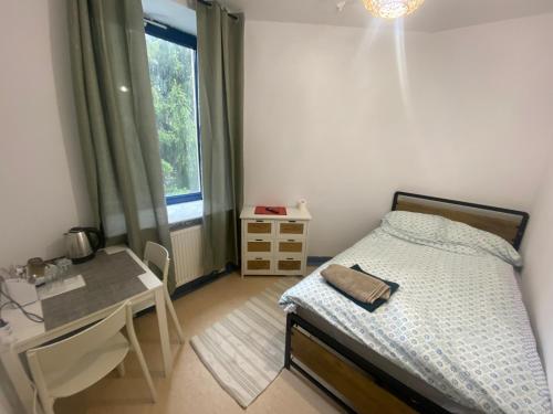 a bedroom with a bed and a desk and a window at Diskrepant Budget Room in Warsaw