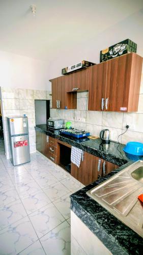 a kitchen with wooden cabinets and a black counter top at Ryma Airbnbs in Mombasa