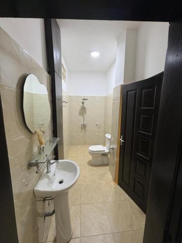 a bathroom with a sink and a toilet and a mirror at La Kribienne in Cotonou