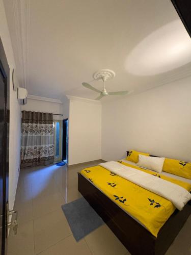 a bedroom with a bed with yellow sheets and a ceiling at La Kribienne in Cotonou