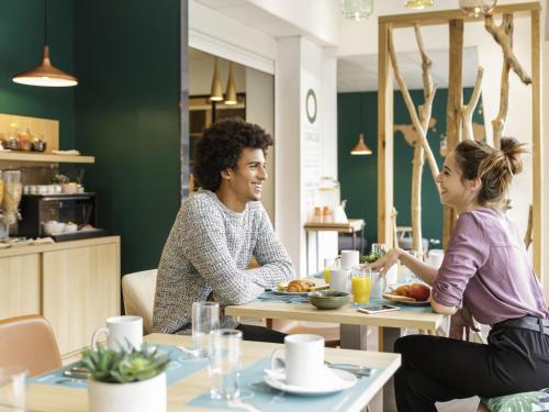 two people sitting at a table in a restaurant at Aparthotel Adagio Access Toulouse St Cyprien in Toulouse