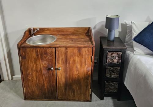 a wooden cabinet with a sink next to a bed at Tarrentoela garden flatlet in Kathu