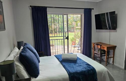 a bedroom with a bed and a large window at Tarrentoela garden flatlet in Kathu