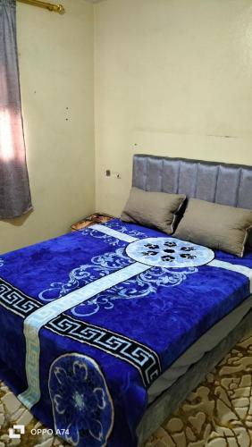 a bedroom with a bed with a blue blanket at شقق دبي مفروشة in Tarfaya