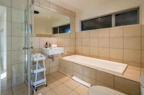 a bathroom with a tub and a sink and a toilet at Miro Ridge in Palm Beach in Waiheke Island