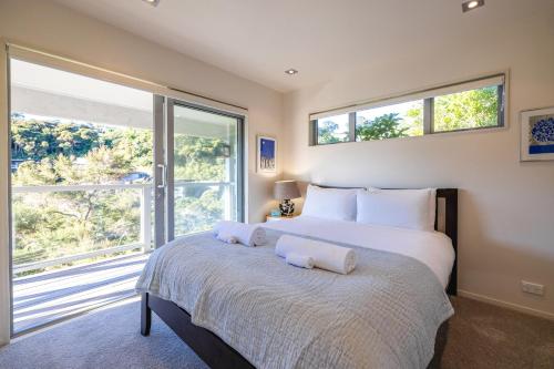 a bedroom with a large bed with two towels on it at Miro Ridge in Palm Beach in Waiheke Island
