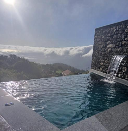 a swimming pool with a waterfall on the side of a building at The Green Valley Porto Moniz in Achadas da Cruz