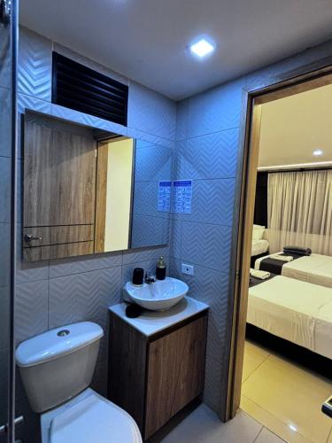 a bathroom with a sink and a toilet and a bed at Aero Hotel Boutique in Bogotá
