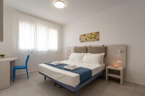 a bedroom with a bed with a blue chair and a table at Sumus Smart Residence in Porto SantʼElpidio