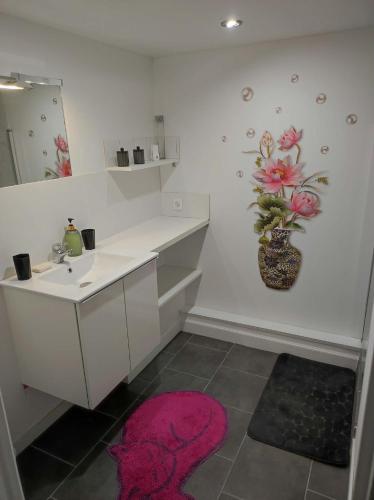 a bathroom with a sink and a vase of flowers on the wall at "La maison fleurie" Sud Vendée 85 in Avrillé