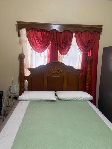 a bedroom with a wooden bed with red curtains at Driftwood Suite in Runaway Bay