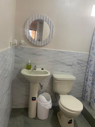 a bathroom with a sink and a toilet and a mirror at El refugio de Lolita in Loja