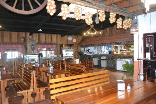 a restaurant with wooden tables and benches and a bar at Hotel Las Brumas in Cartago