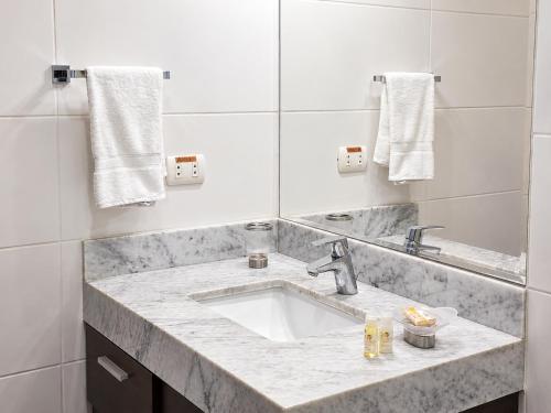 a white bathroom with a sink and a mirror at Diez Canseco by 2W Aparments Service in Lima
