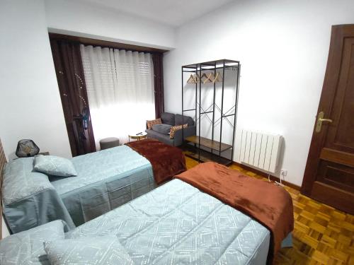 a room with two beds and a chair in it at H & L Fogar do Camiño in Padrón