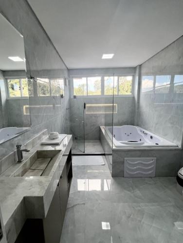 a large bathroom with a tub and a sink at Hotel Pasqualotto in Chopinzinho