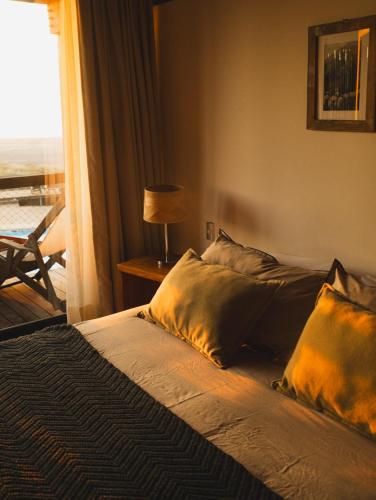 a bedroom with a bed with pillows and a window at Hotel Punta Sirena in Curanipe
