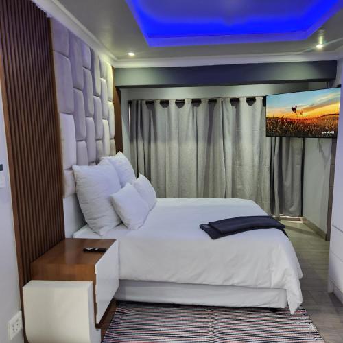 a bedroom with a white bed with a blue ceiling at Cozy & Modern Apartment -Self Catering in Pretoria