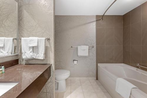 a bathroom with a tub and a toilet and a sink at Best Western PLUS The Arden Park Hotel in Stratford