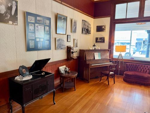 ein Zimmer mit einem Klavier und einem Schreibtisch mit einem Laptop in der Unterkunft Richca Heritage Hotel in Chilliwack