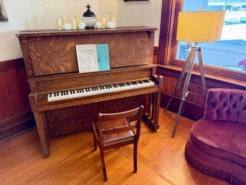 ein Klavier in einem Zimmer mit einem Stuhl und einer Lampe in der Unterkunft Richca Heritage Hotel in Chilliwack