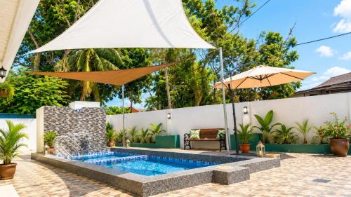 a swimming pool with an umbrella and a swimming poolvisor at Villa Ar Raudhah Kuala Terengganu in Kampong Cherong Baru