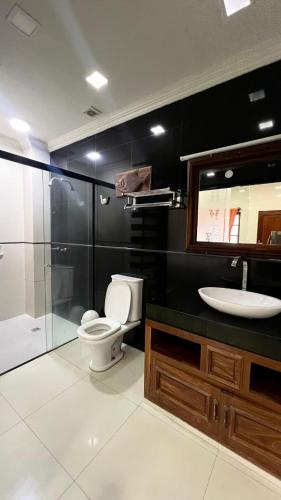 ein Badezimmer mit Toilette und Glasdusche in der Unterkunft Hotel Jacarandá Suites in Trinidad