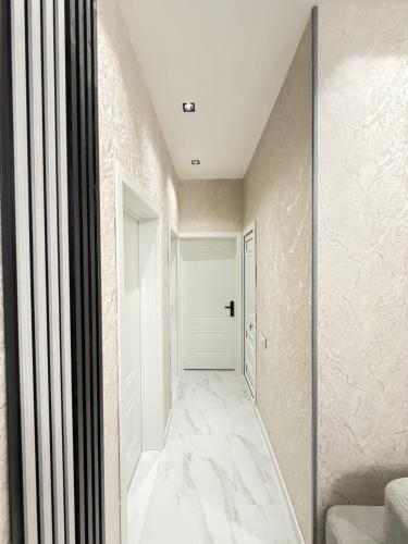 a hallway with white marble floors and a white door at White Dream Villa in Mərdəkan