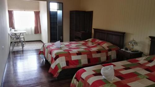 a hotel room with two beds and a table at Hotel Las Brumas in Cartago