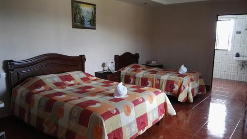 a bedroom with two beds and a shower at Hotel Las Brumas in Cartago