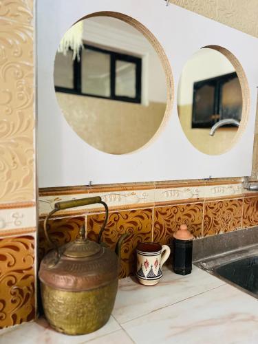 a bathroom sink with a large pot and two mirrors at Black Pearl surf yoga and skate house in Tamraght Ouzdar