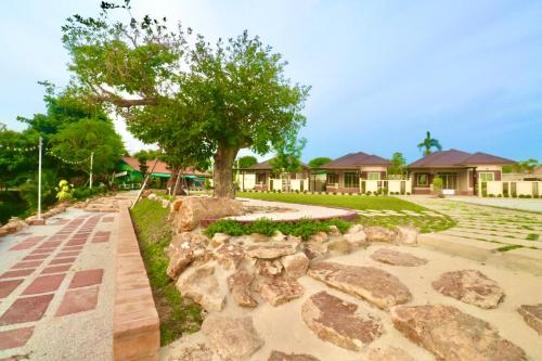 a garden with rocks and a tree in front of a house at รักแรกพบรีสอร์ทสัตหีบ in Sattahip